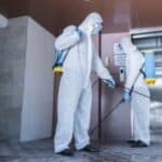 due addetti in tuta bianca effettuano nelle aree comuni sanificazione nel condominio