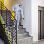 adetto in tuta bianca sanificazione scale di condominio